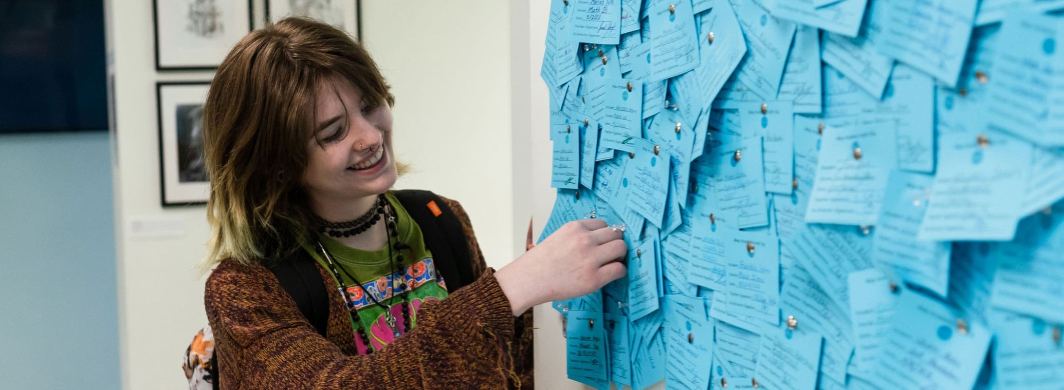 Student at comment board smiling.